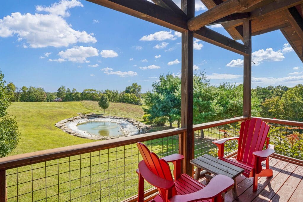 Covered deck with red chairs overlooking pond