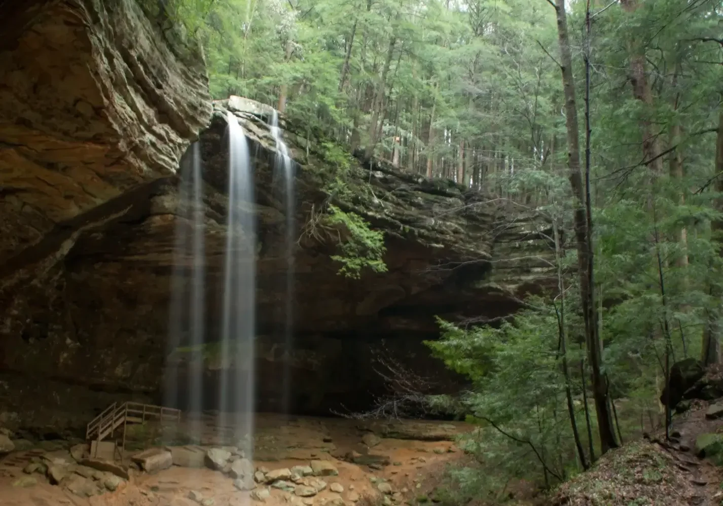 Secluded forest waterfall cascading into sandstone alcove